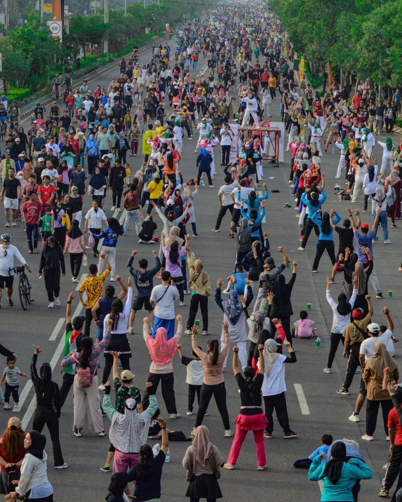 Thousands of people exercising together with raised arms on a closed city road – Largest Mass Workout world record idea